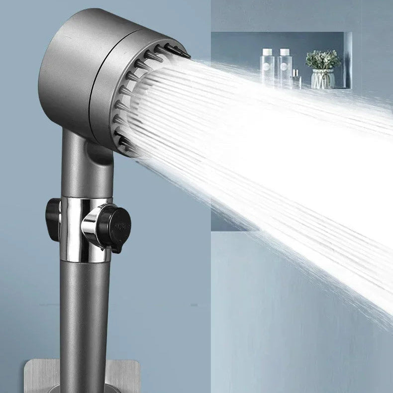 Handheld shower head with water flowing, mounted on a wall with a sink in the background.